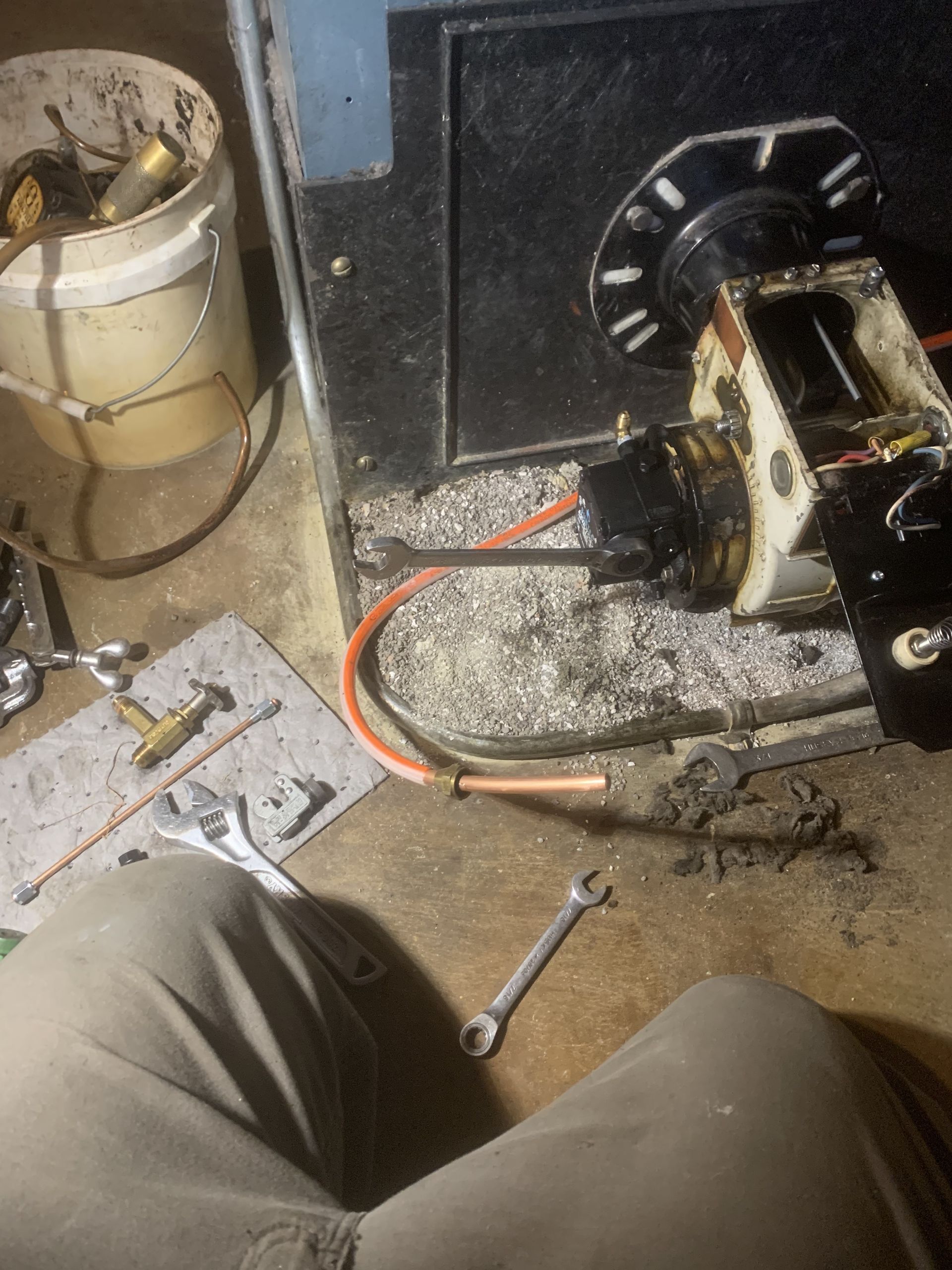 A person is working on a machine with tools on the floor.