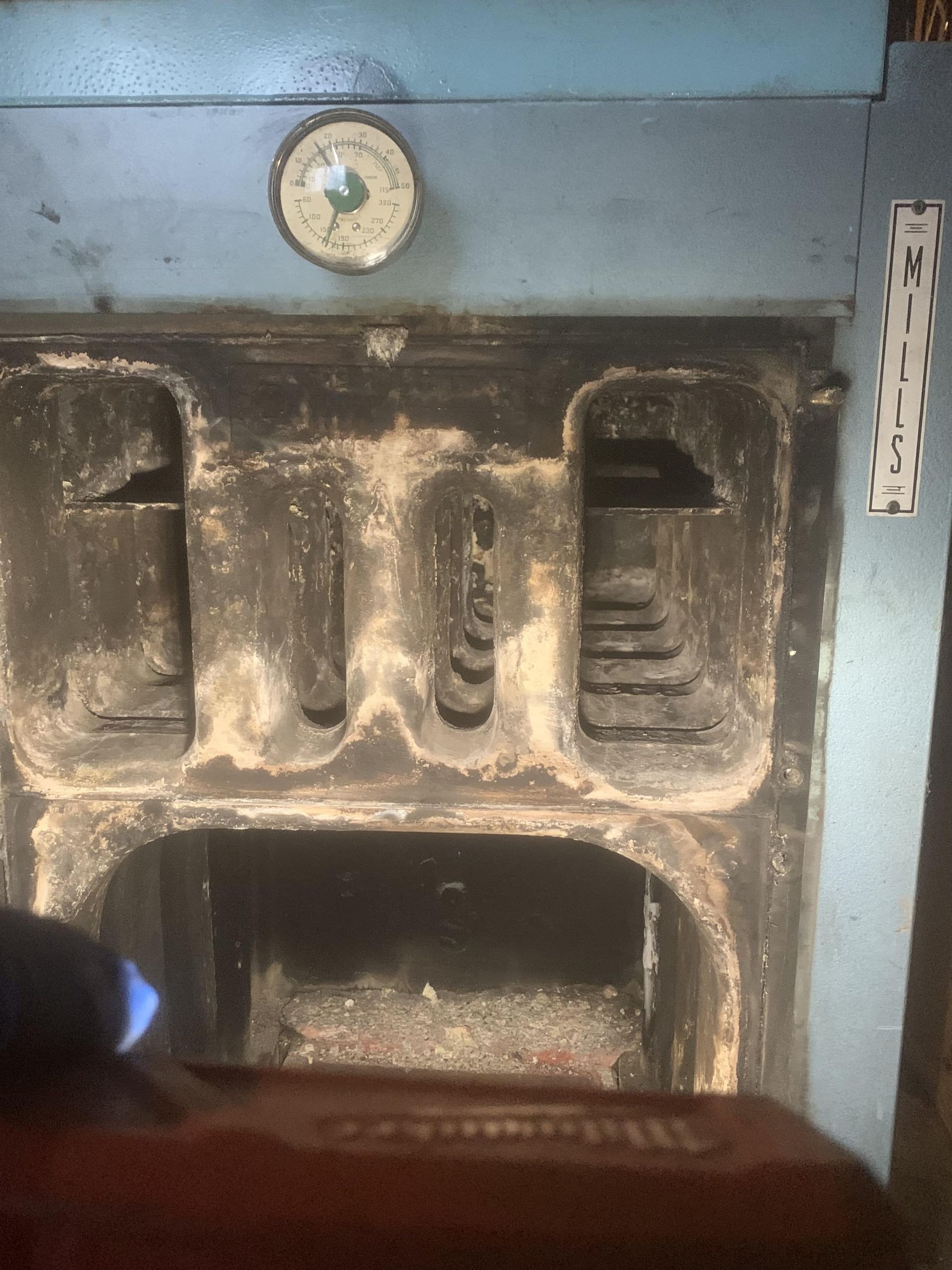 A dirty stove with a thermometer on top of it.