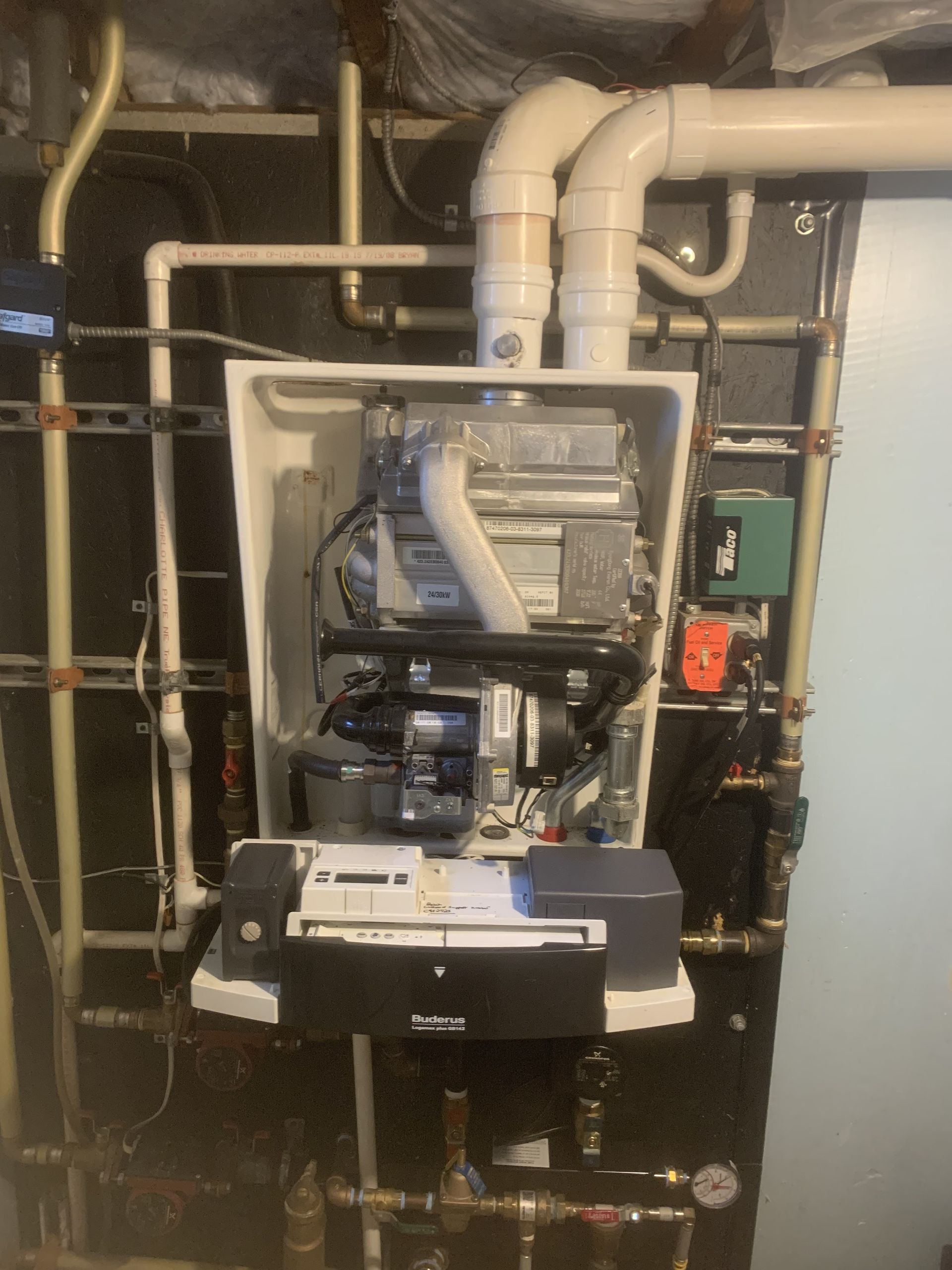 A boiler is sitting in a room with pipes coming out of it