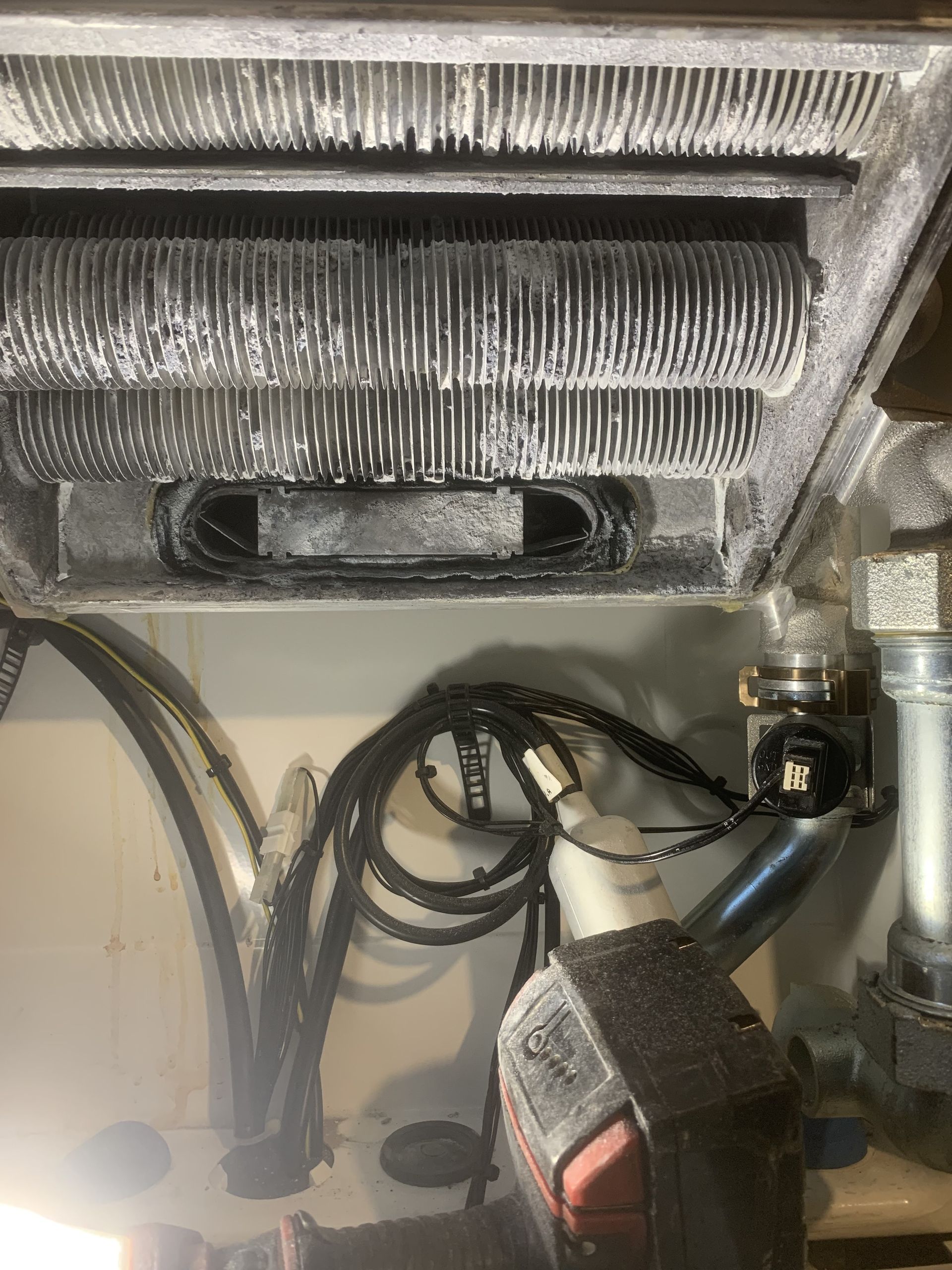 A close up of a heater with a drill and wires coming out of it.