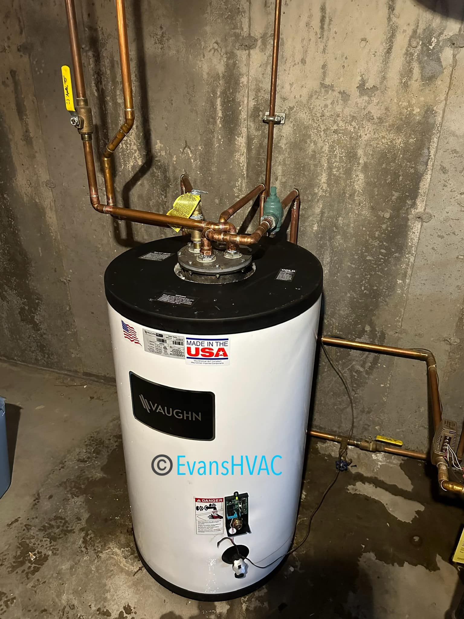 A water heater is sitting in a basement next to a wall.