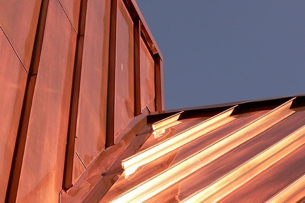 A close up of a copper roof with a blue sky in the background.