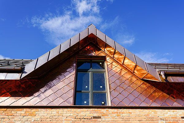 A brick building with a copper roof and a window.