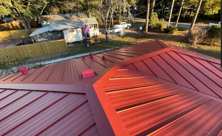 A red metal roof is being painted on a house.