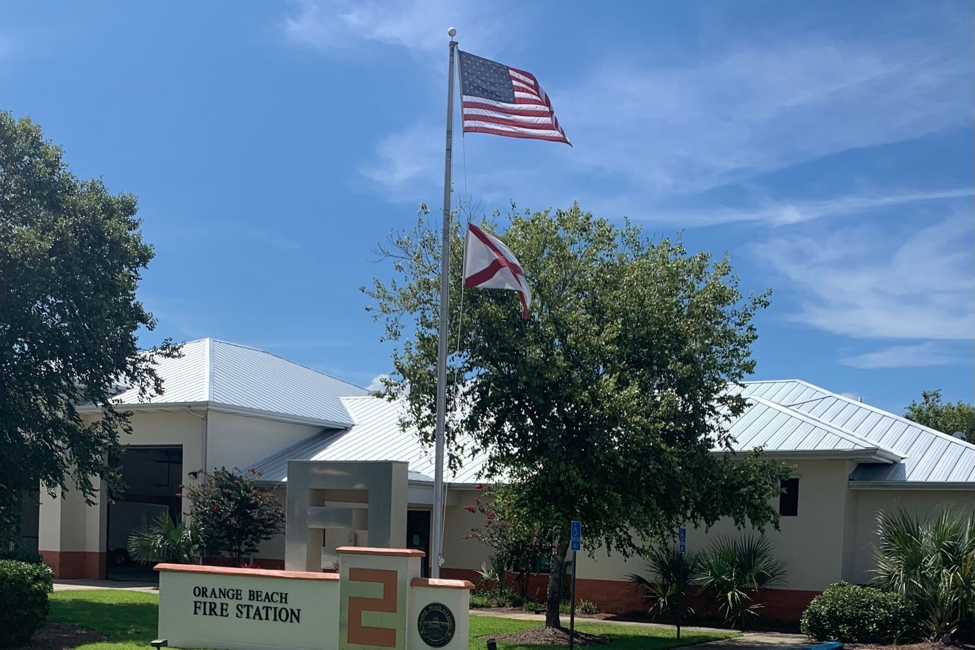 An american flag is flying in front of a fire station