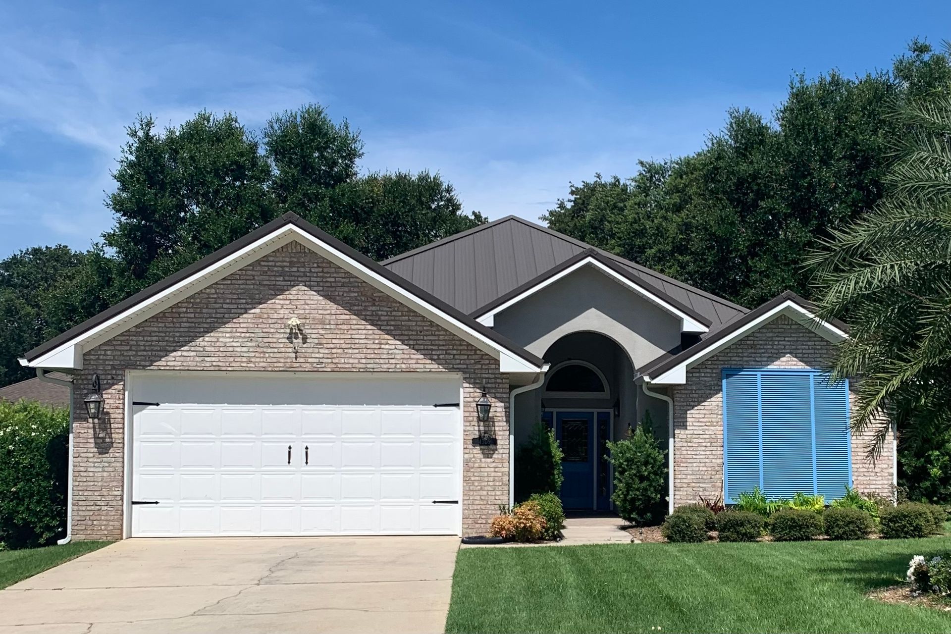 A brick house with a white garage door and a blue window