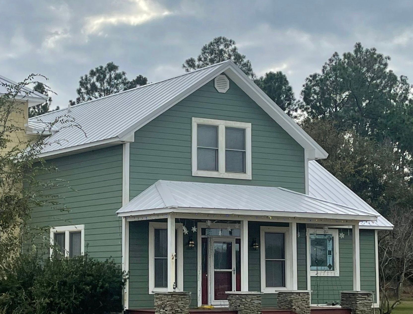 A green house with a white roof and a red door