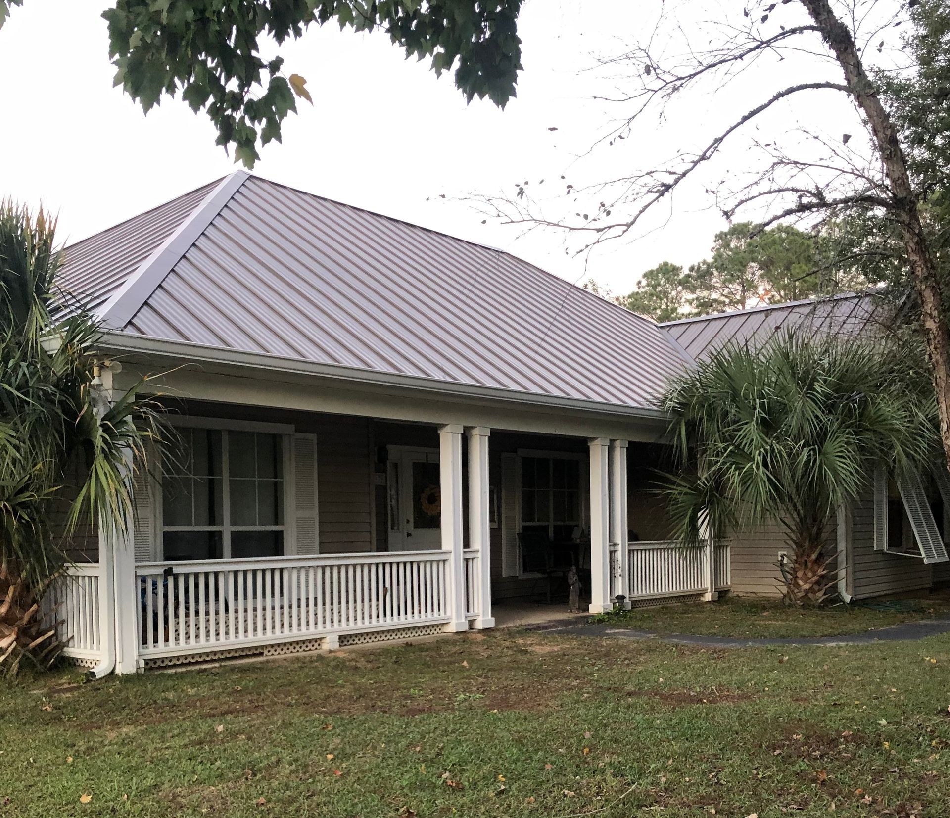 A house with a gray metal roof and a white porch.