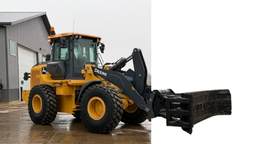 Yellow front-end loader with a bucket attachment parked beside a building on a wet surface