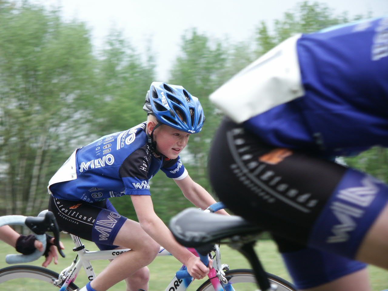 Wielrenner met blauwe helm en shirt, die buiten aan het racen is.