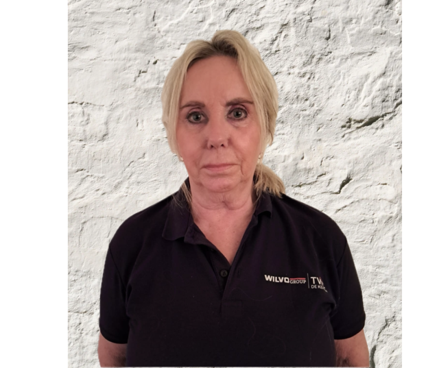 Een blond persoon met oorringen kijkt de kijker aan, gekleed in een wit shirt tegen een witte achtergrond.