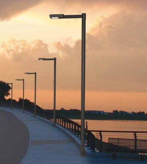 Eine Reihe von Straßenlaternen neben einem Gewässer bei Sonnenuntergang