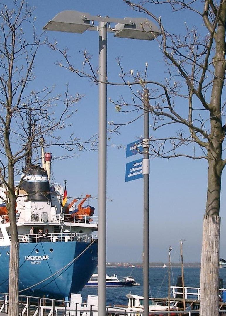 Ein großes blaues Schiff liegt neben einer Straßenlaterne angedockt