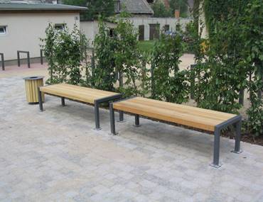 Zwei Holzbänke stehen nebeneinander auf einem gepflasterten Gehweg.