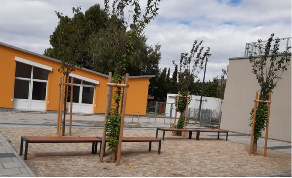 Eine Reihe von Bänken mit Bäumen vor einem Gebäude