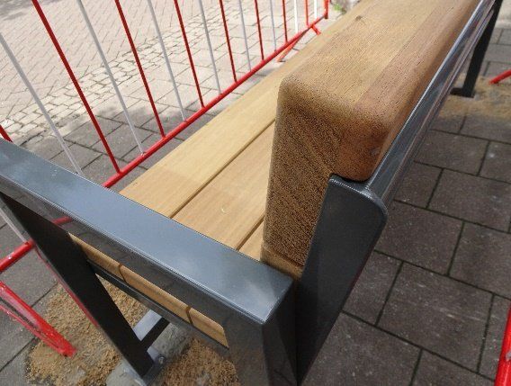 Eine Holzbank steht vor einem rot-weißen Zaun