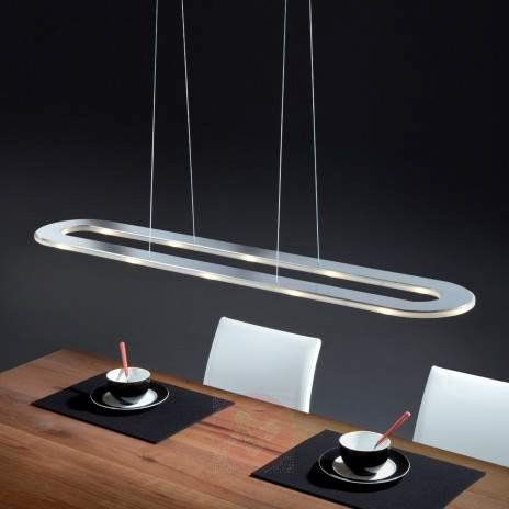 Eine lange Pendelleuchte hängt über einem hölzernen Esstisch