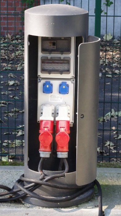 Zwei rote und weiße Steckdosen sind mit einem Metallmast verbunden