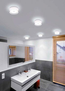 Ein Badezimmer mit Waschbecken, Spiegel und Jalousien