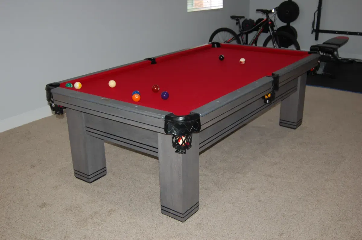 Pool table with red felt, gray frame, and balls scattered on the surface.