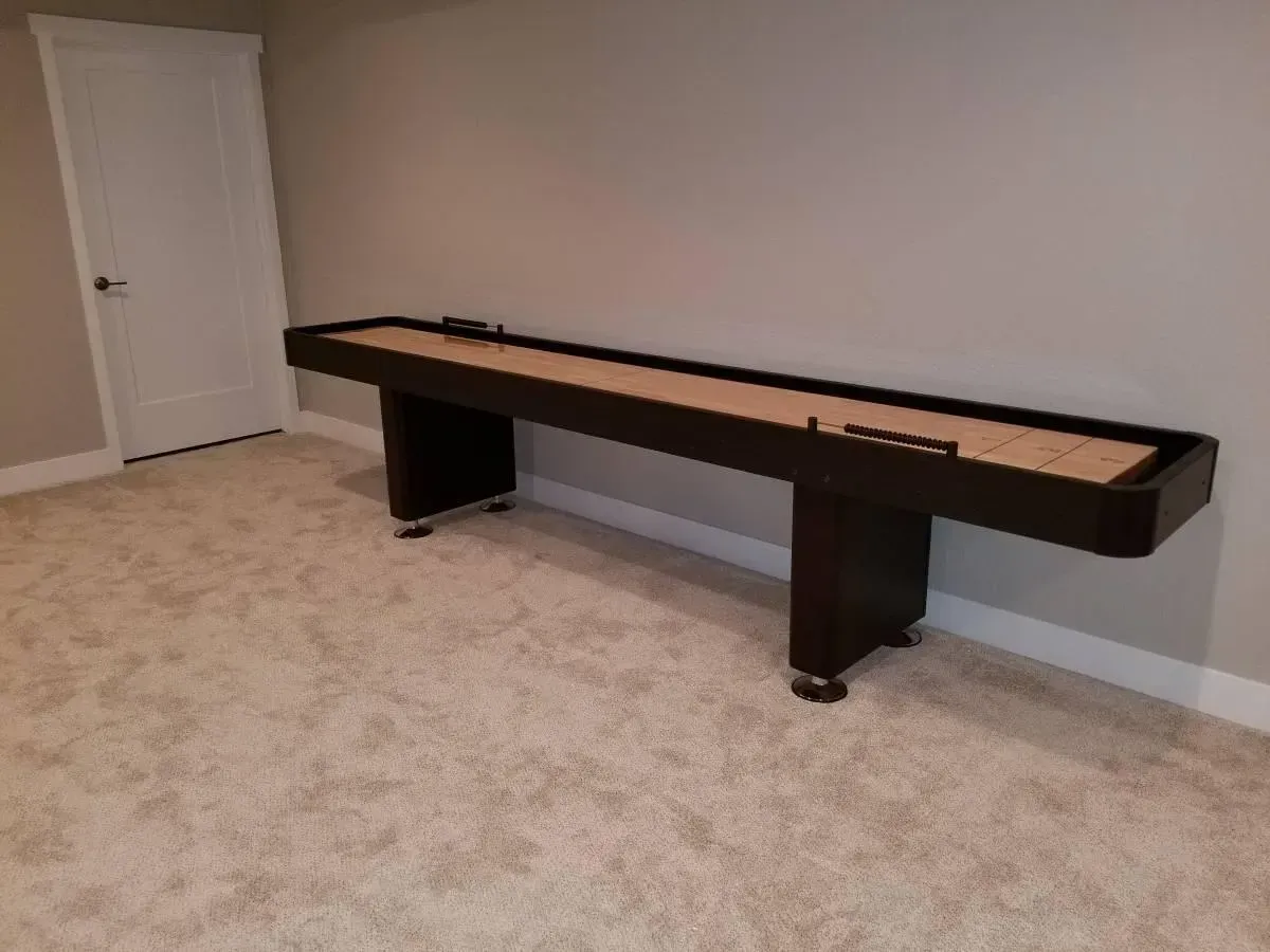 Shuffleboard table in a room with tan carpet and light gray walls.