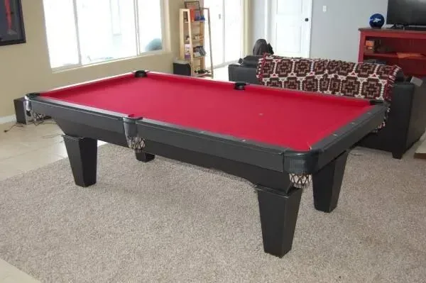 Pool table with red felt in a living room, black and silver details.