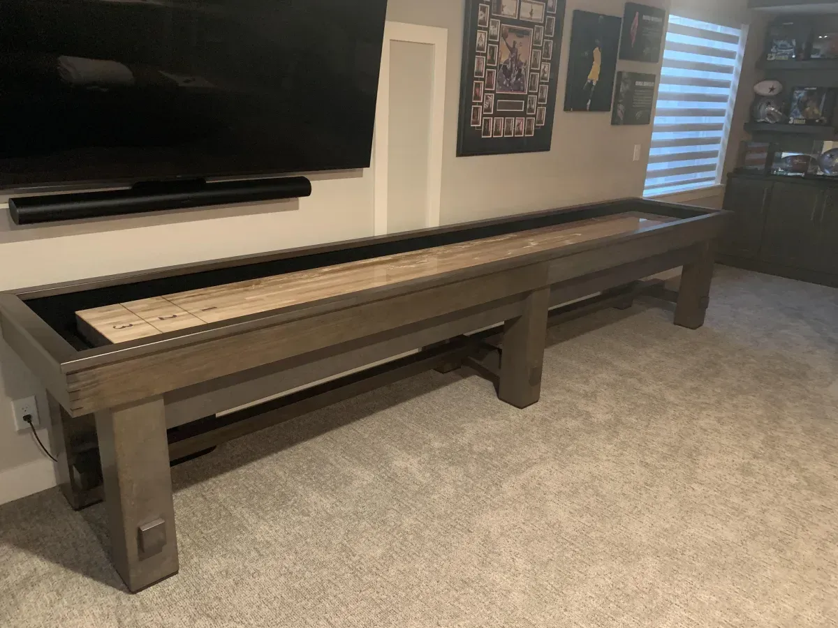 Shuffleboard table in a room with a TV and a window.