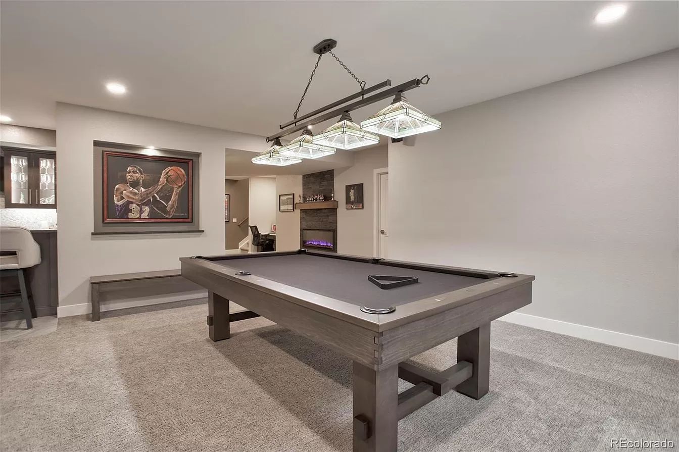 Pool table in a game room with gray walls, carpet, and a decorative light fixture.