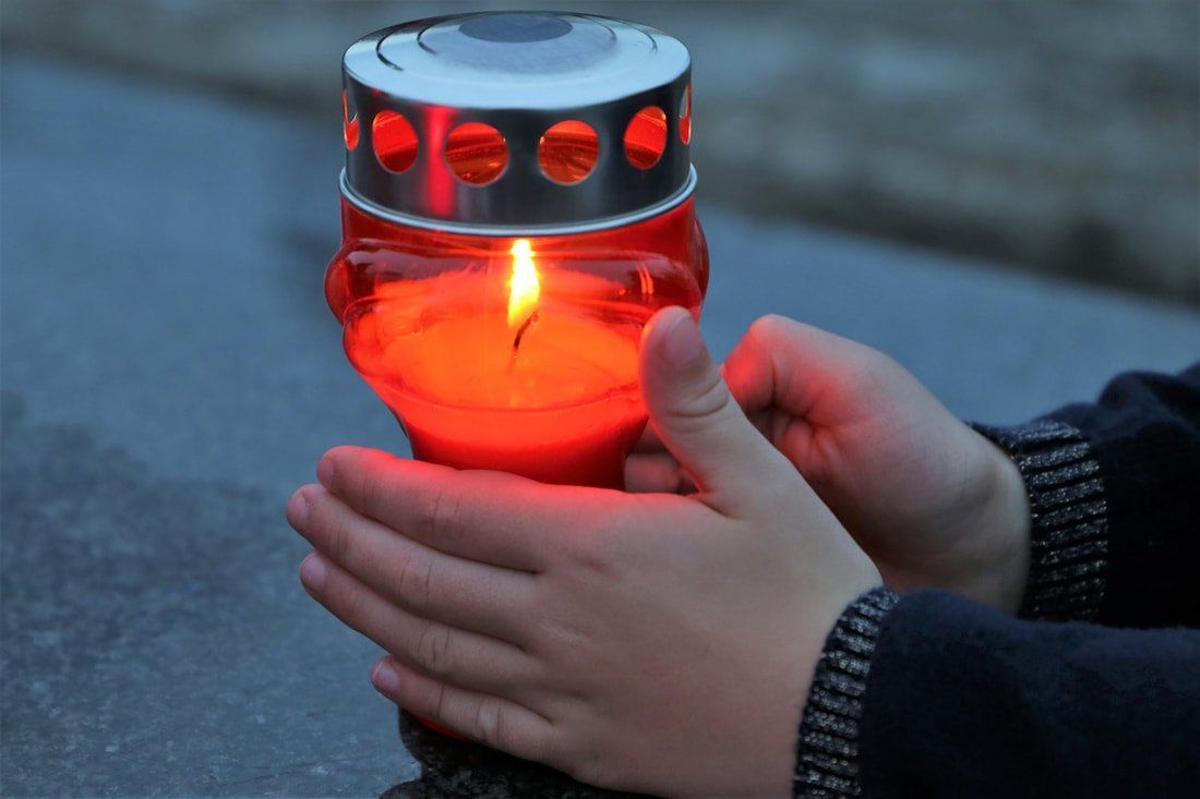 A person is holding a red candle in their hands