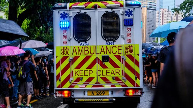 An ambulance is driving down a street in the rain.