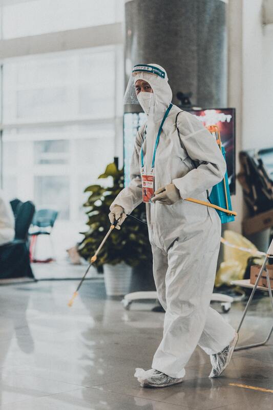 A man in a protective suit is spraying a room with a sprayer.