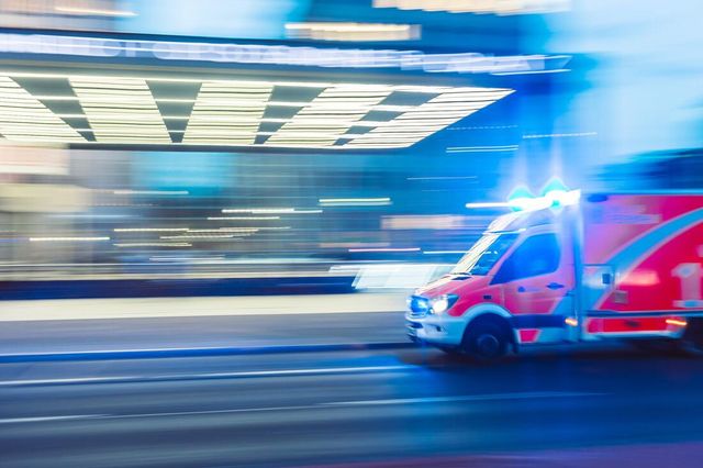 An ambulance is driving down a city street at night.