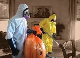 A group of people in protective suits are cleaning a living room.