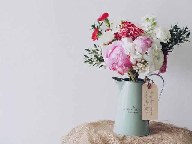 A vase filled with pink and white flowers with a tag attached to it.