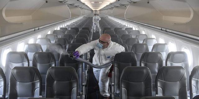 A man is cleaning the inside of an airplane with a vacuum cleaner.