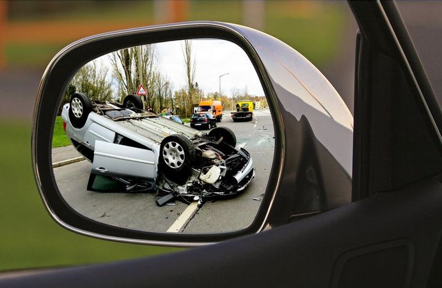 A car accident is reflected in the rear view mirror of a car.