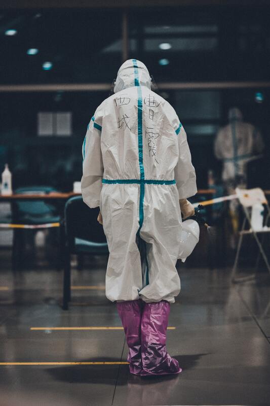 A person in a protective suit is walking down a hallway.