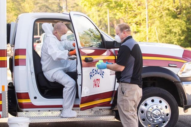 A man in a protective suit is getting out of a rescue truck.