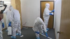 A group of people in protective suits are cleaning a room.