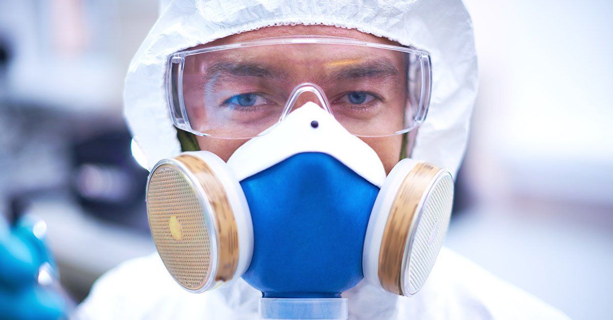 A man wearing a gas mask and goggles in a lab.