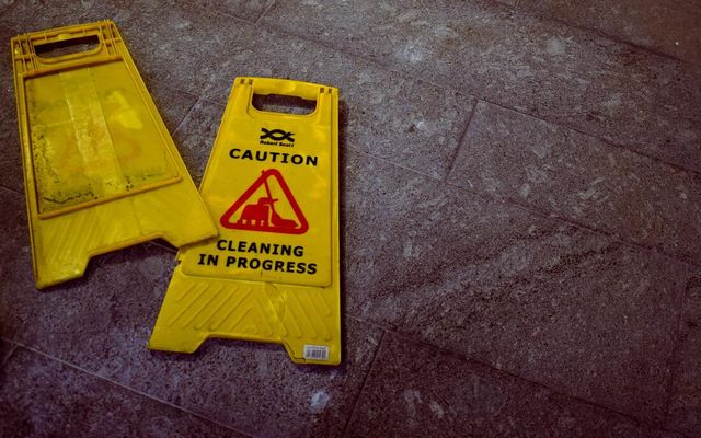 Two yellow caution signs are sitting on a tiled floor.