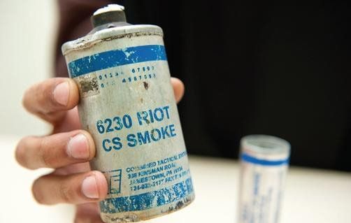 A person is holding a can of cs smoke in their hand.