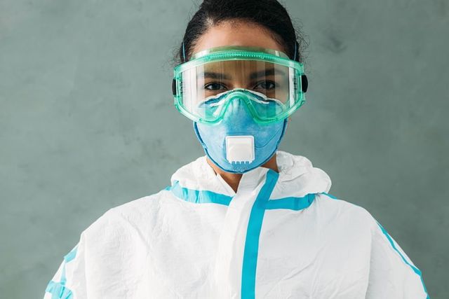 A woman wearing a protective suit , mask and goggles.