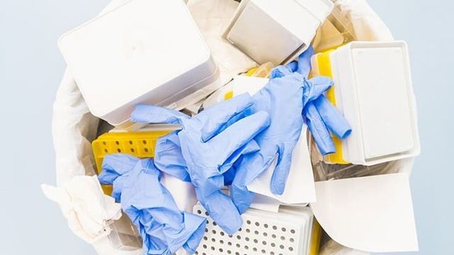 A trash can filled with gloves and boxes on a blue background.