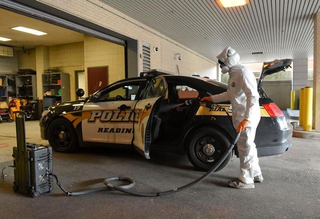 A man in a protective suit is cleaning a police car