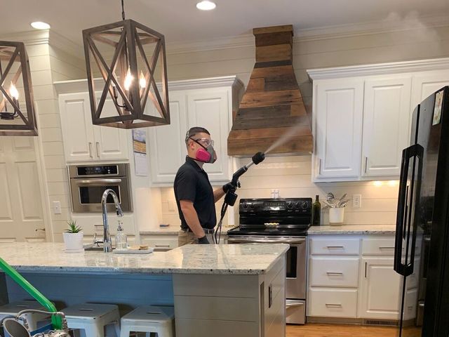 A man is spraying a kitchen with a high pressure washer.