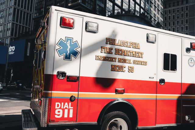 An ambulance is parked on the side of the road in a city.