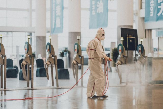 A man in a protective suit is cleaning the floor of an airport.