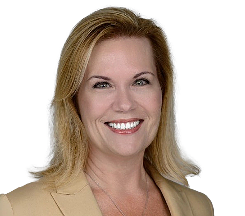 Carollyn Sorto in a tan blazer smiles; studio headshot against white background.