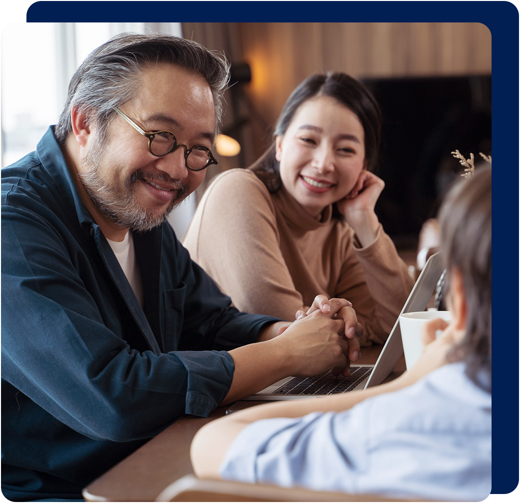 Smiling family around a laptop, discussing something. Warm lighting, cozy setting.
